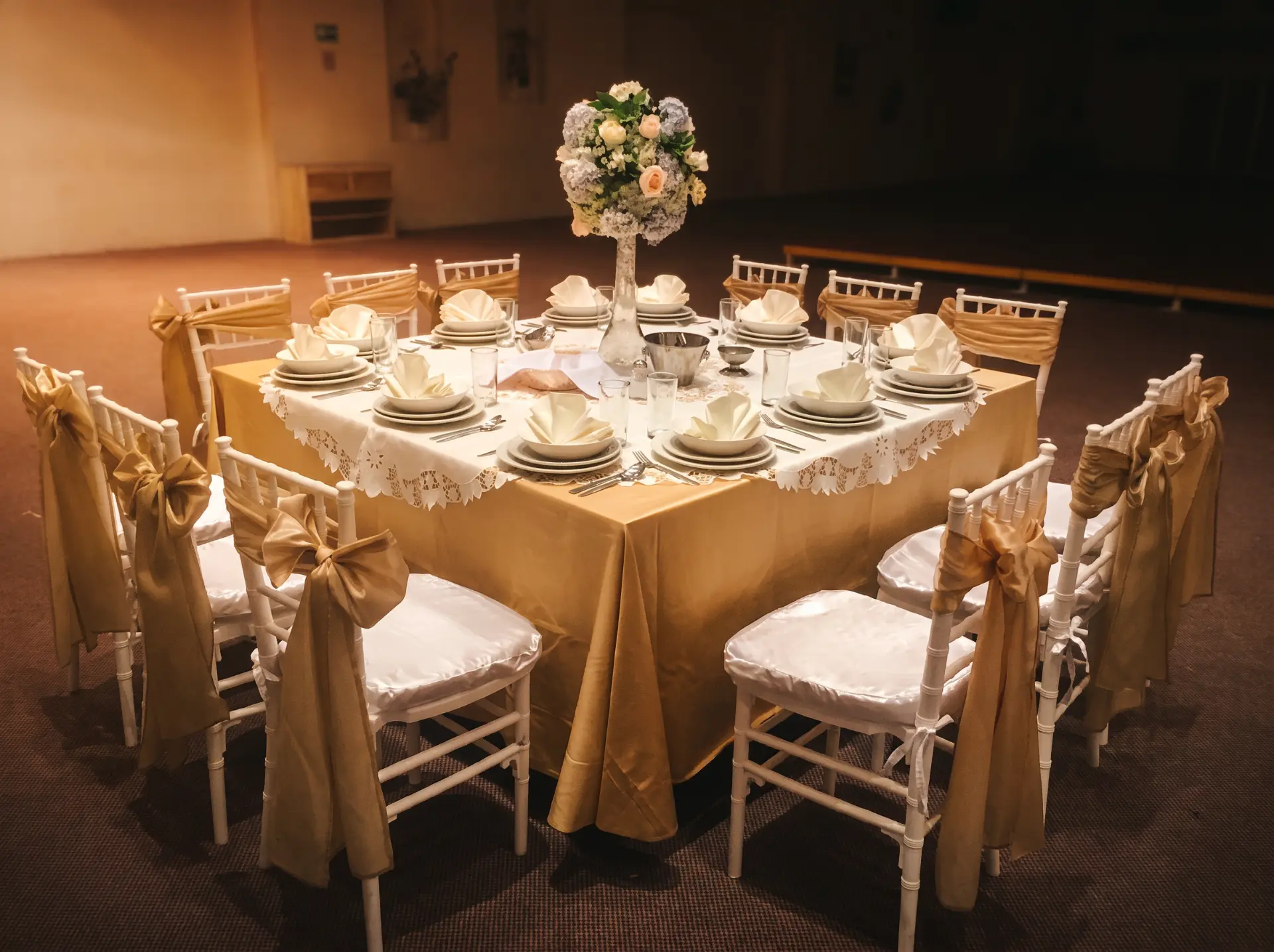 Mesa formal con mantel dorado y centro floral