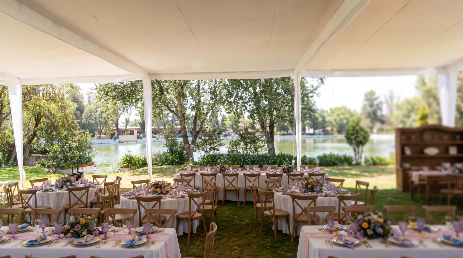 Carpa junto al lago con mesas vestidas para evento